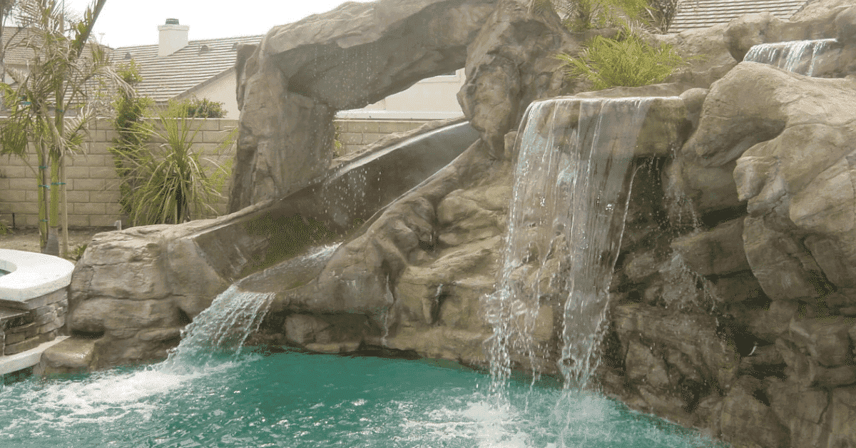Swimming pool with a rock waterslide built by Thomas Pools. 